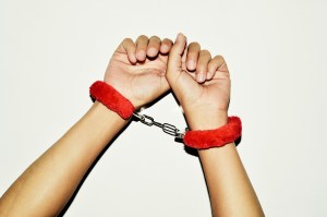 A pair of hands in red furry handcuffs
