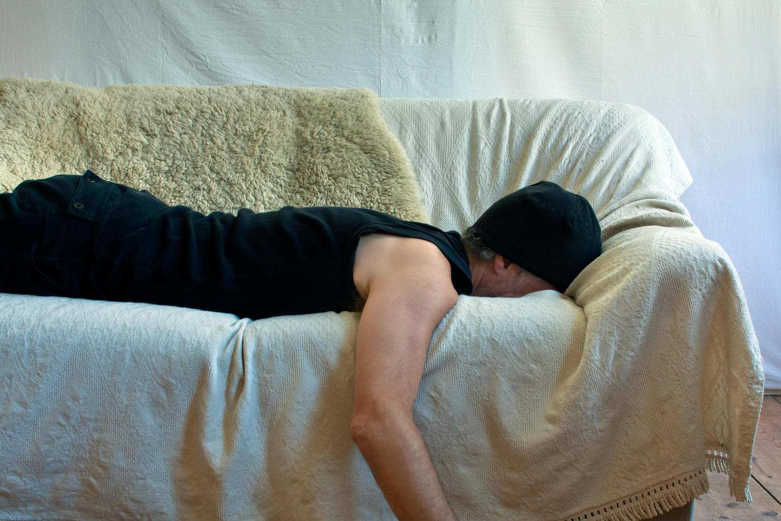 Mann liegt beim Runterkommen vom Hangover mit Gesicht nach unten auf einer Couch