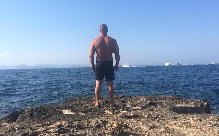 Ein muskulöser Mann steht in Badehose am Meer