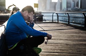 Man on a park bench holding his head in his hands