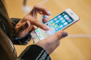 Ilustrasi perempuan memakai iPhone. Ternyata Apple dan Samsung curang memaksa kita beli ponsel terbaru mereka