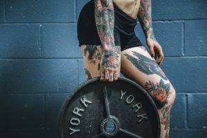 Tattooed young woman carrying a weight plate