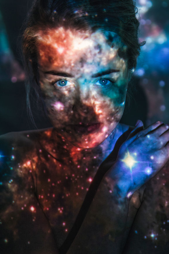 A pair of eyes peers through a projection of stars