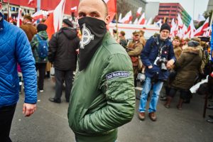 mężczyzna w masce z krzyżem celtyckim na marszu niepodległości