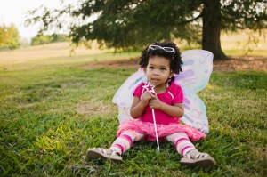 toddler in the grass with butterfly wings on