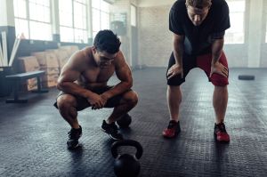 Two exhausted men hunched over and recovering from a workout