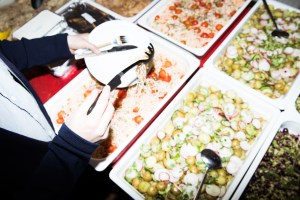 Mand skovler mad op i en kantinebuffet