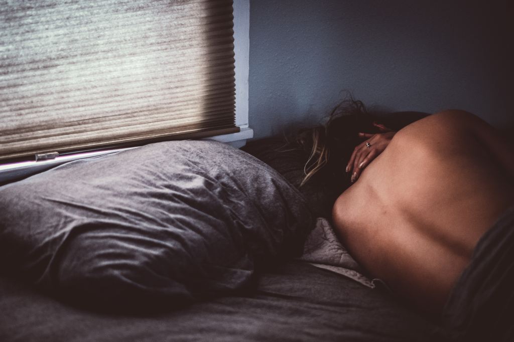 Woman lying on bad with bare back facing camera