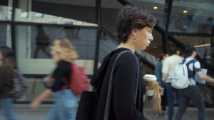 Jonge vrouw met koffie to-go beker en bruin papieren tasje op straat