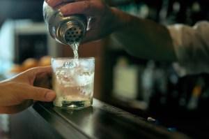 Foto van een cocktail die vanuit een shaker in een glas wordt geschonken.