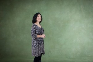 Yoko Shimomoura poses in front a green backdrop, she is a composer of Kingdom Hearts.