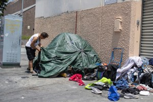 A homeless individual adjusts his tent on Skid Row street in Downtown Los Angeles on Friday, May 31, 2019. (