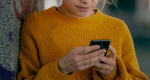 Sprache und Depression: Eine junge Frau mit Handy in der Hand