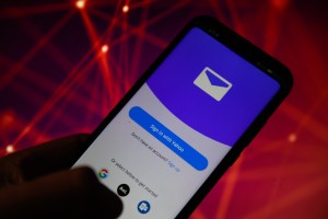 A hand holding a phone displaying Yahoo Mail.