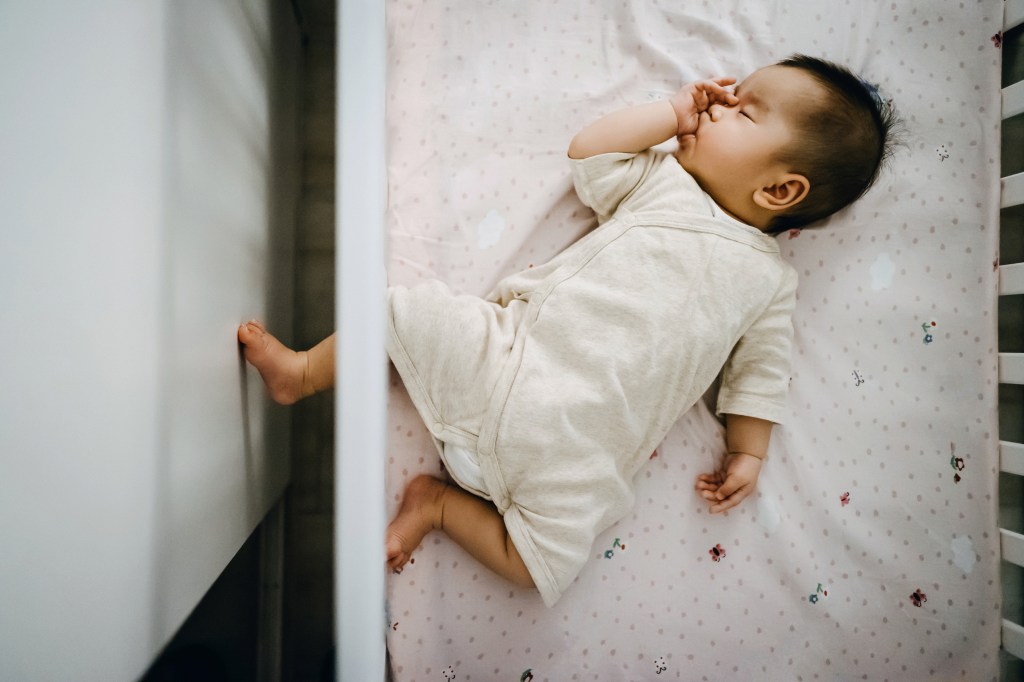 A baby sleeps on a crib its back