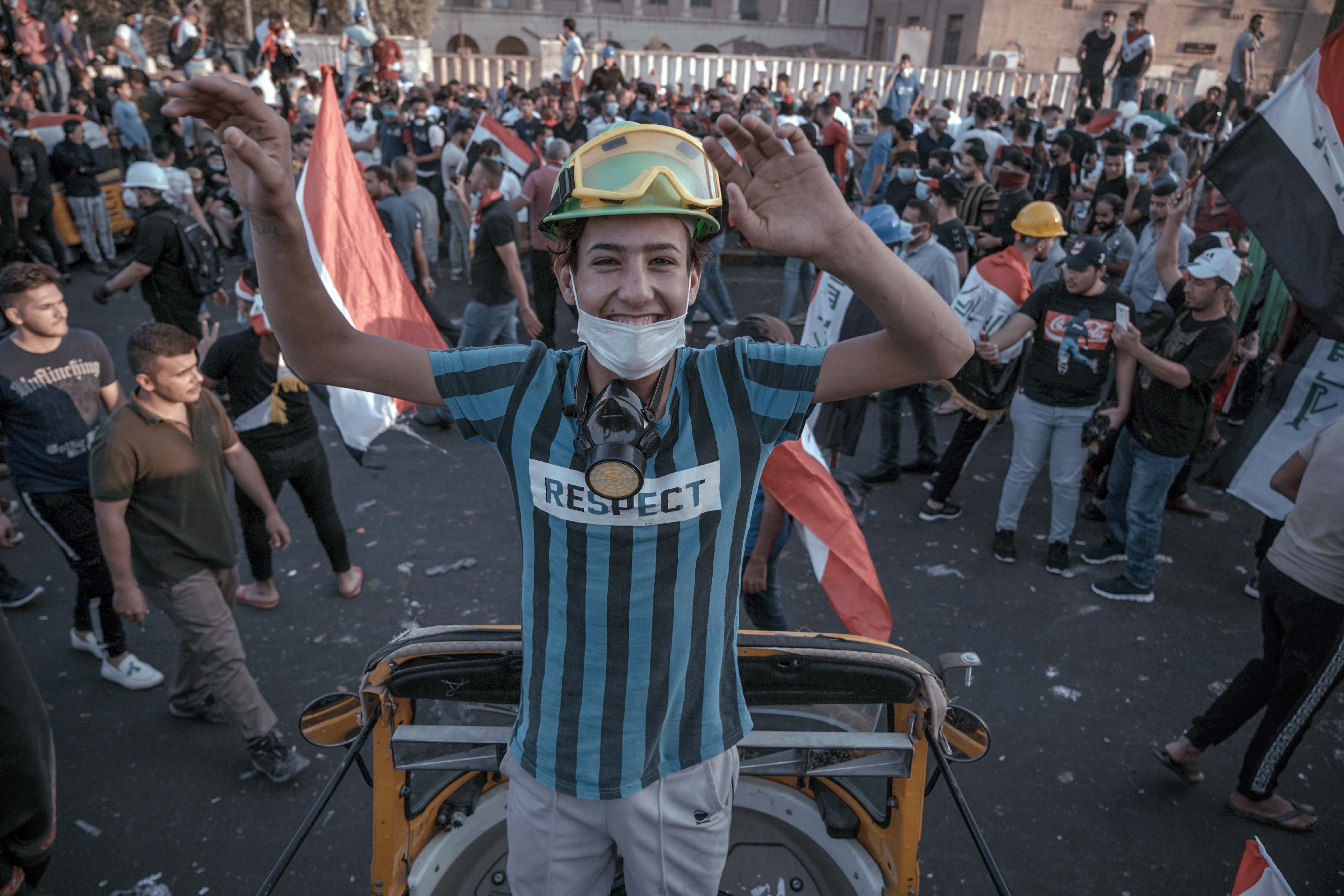 A smiling boy in a helmet and goggles at a demonstration in Baghdad, Iraq