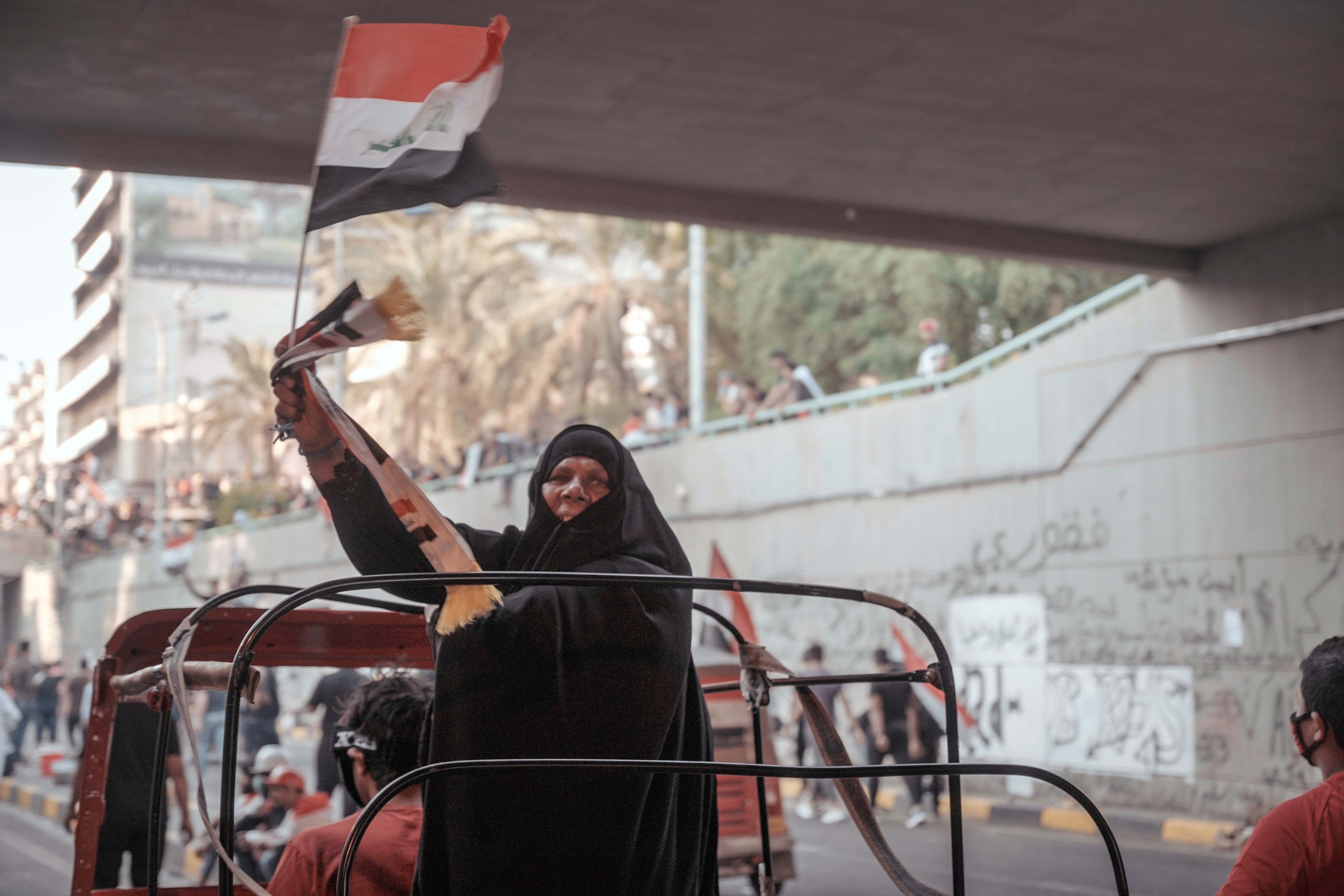 A woman waves a flag during the demonstrations in Baghdad, Iraq