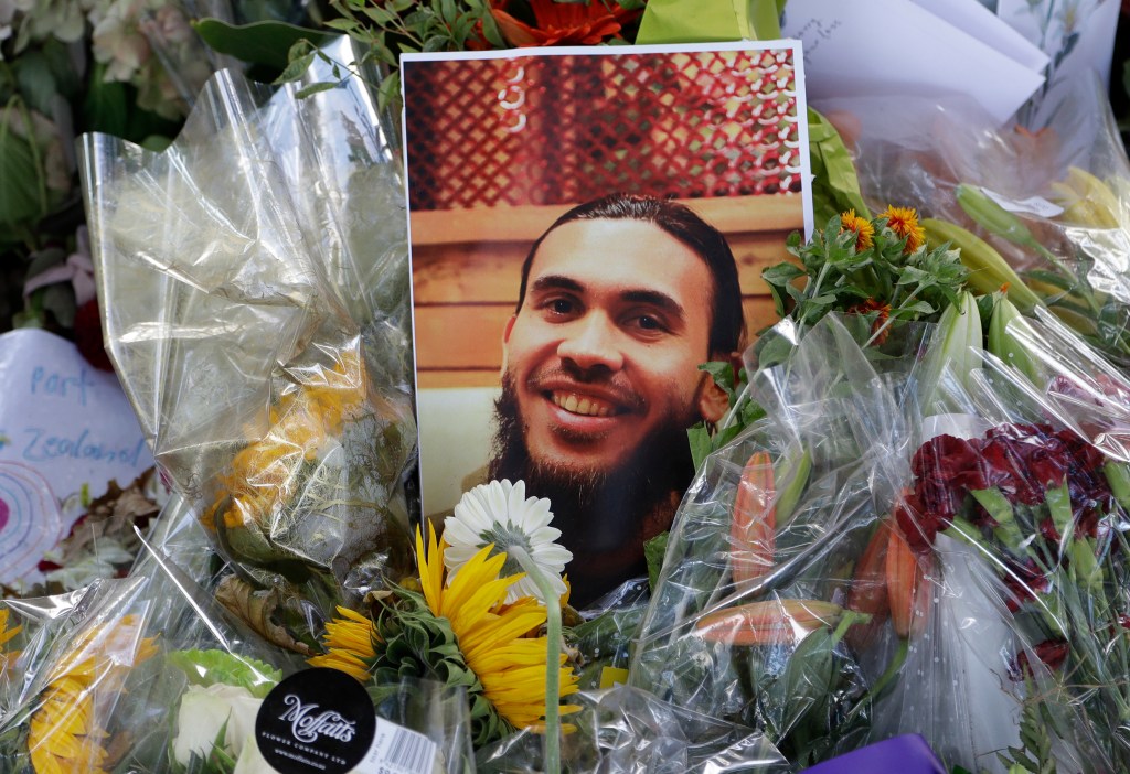 A photo tribute for Christchurch mosque shooting victim Tariq Omar lies amid mounds of flowers across the road from the Al Noor mosque in Christchurch, New Zealand Tuesday, March 19, 2019.