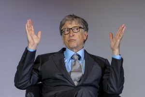 Bill Gates onstage holding his hands up.