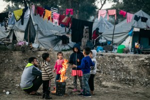 Without adequate shelter or winter clothing, Tajj, 37, his daughter Sara, 9, and other refugees from Afghanistan and Syria rely on a small fire for warmth on January 4, 2020, in Lesbos, Greece. ​(Maranie R. Staab/VICE News)