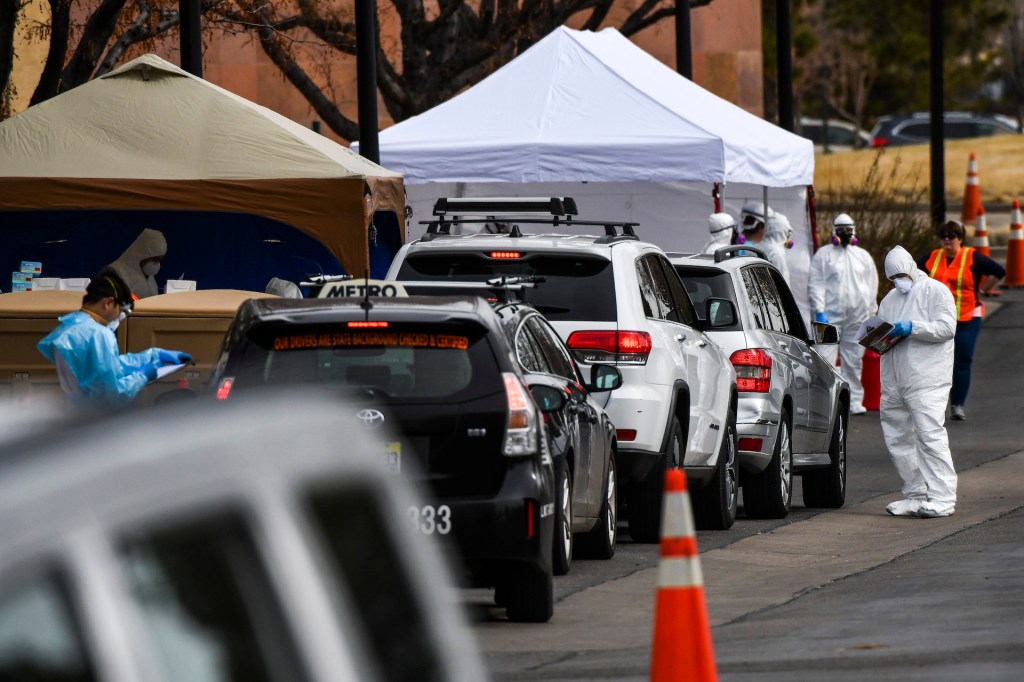 Healthcare workers from the Colorado Department of Public Health and Environment test people for COVID-19 at the state's first drive-up testing center on March 12, 2020 in Denver, Colorado.