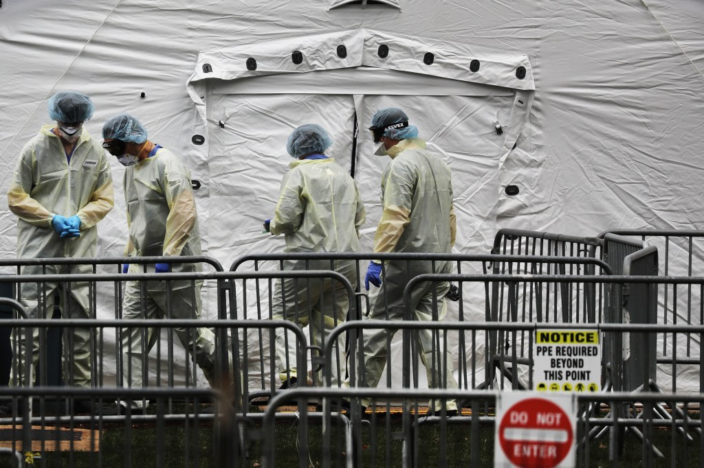 People in scrubs, hairnets and face masks stand at the center to a hospital tent set up by Samaritan's Purse in Central Park.