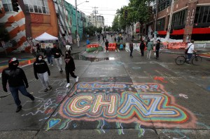 People walk past street art that reads "Welcome to CHAZ," Thursday, June 11, 2020, inside what is being called the "Capitol Hill Autonomous Zone" in Seattle.
