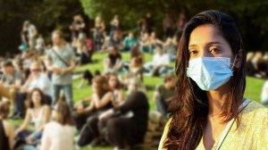 Eine Frau mit Maske vor einer Gruppe Menschen, die im Park sitzen