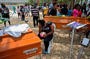 Un familiar llora junto a los ataúdes de dos de los cinco jóvenes asesinados en un campo de caña de azúcar, durante su funeral en el distrito de Aguablanca, al este de Cali, Colombia, el 13 de agosto de 2020. (AFP vía Getty Images/Luis Robayo