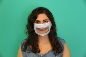 Image of woman smiling while wearing mask with transparent plastic over her mouth