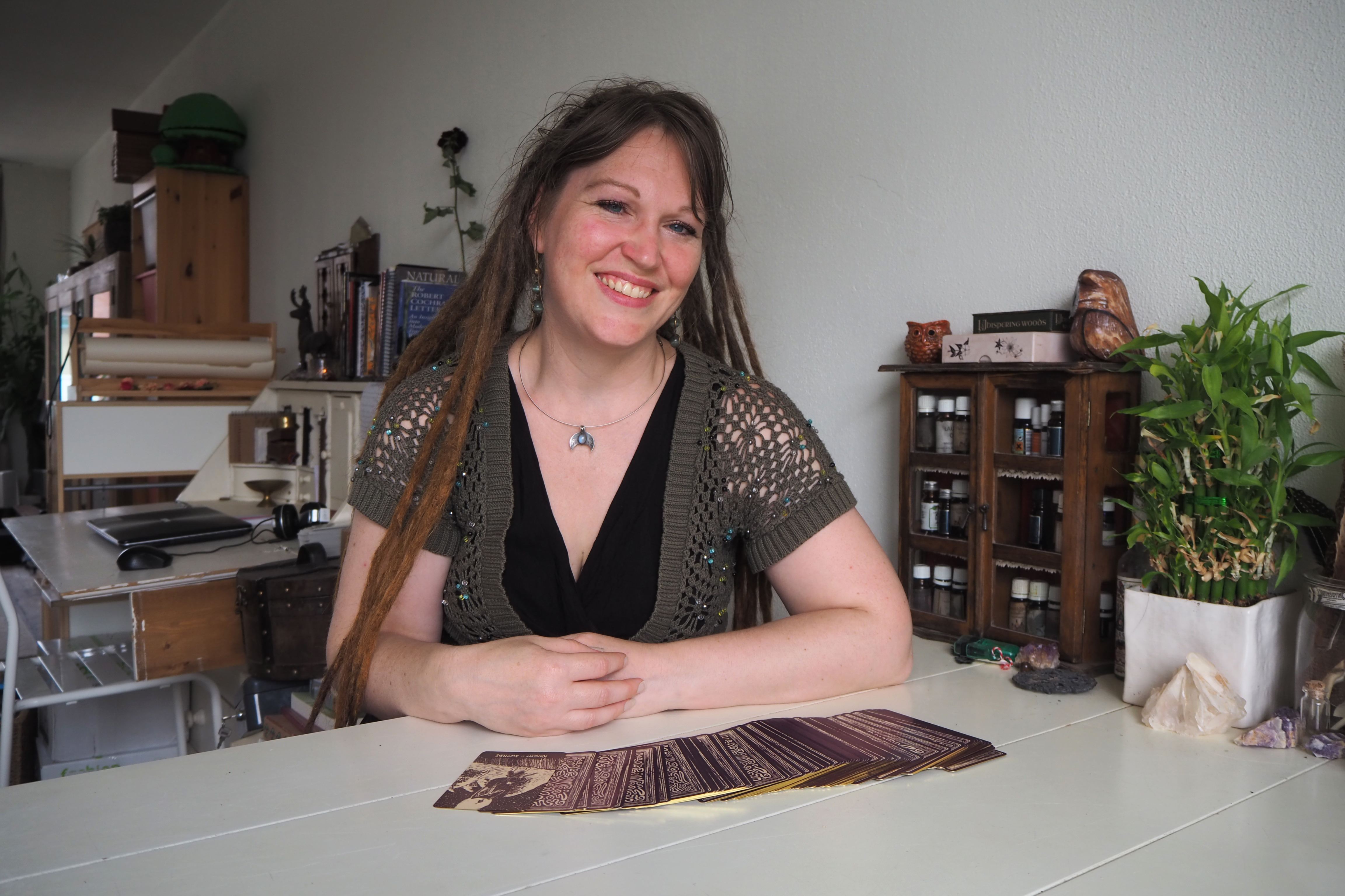 Eine junge Frau mit langen roten Dreadlocks sitzt am Tisch vor aufgefächerten Tarotkarten