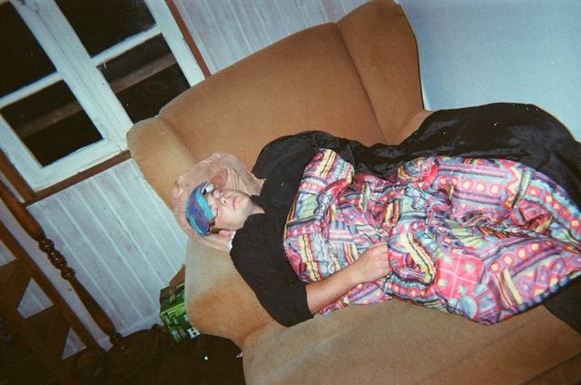 Young guy wearing a cap passed out on a large armchair.