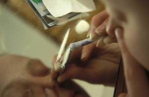 Woman takes cocaine using bank note.