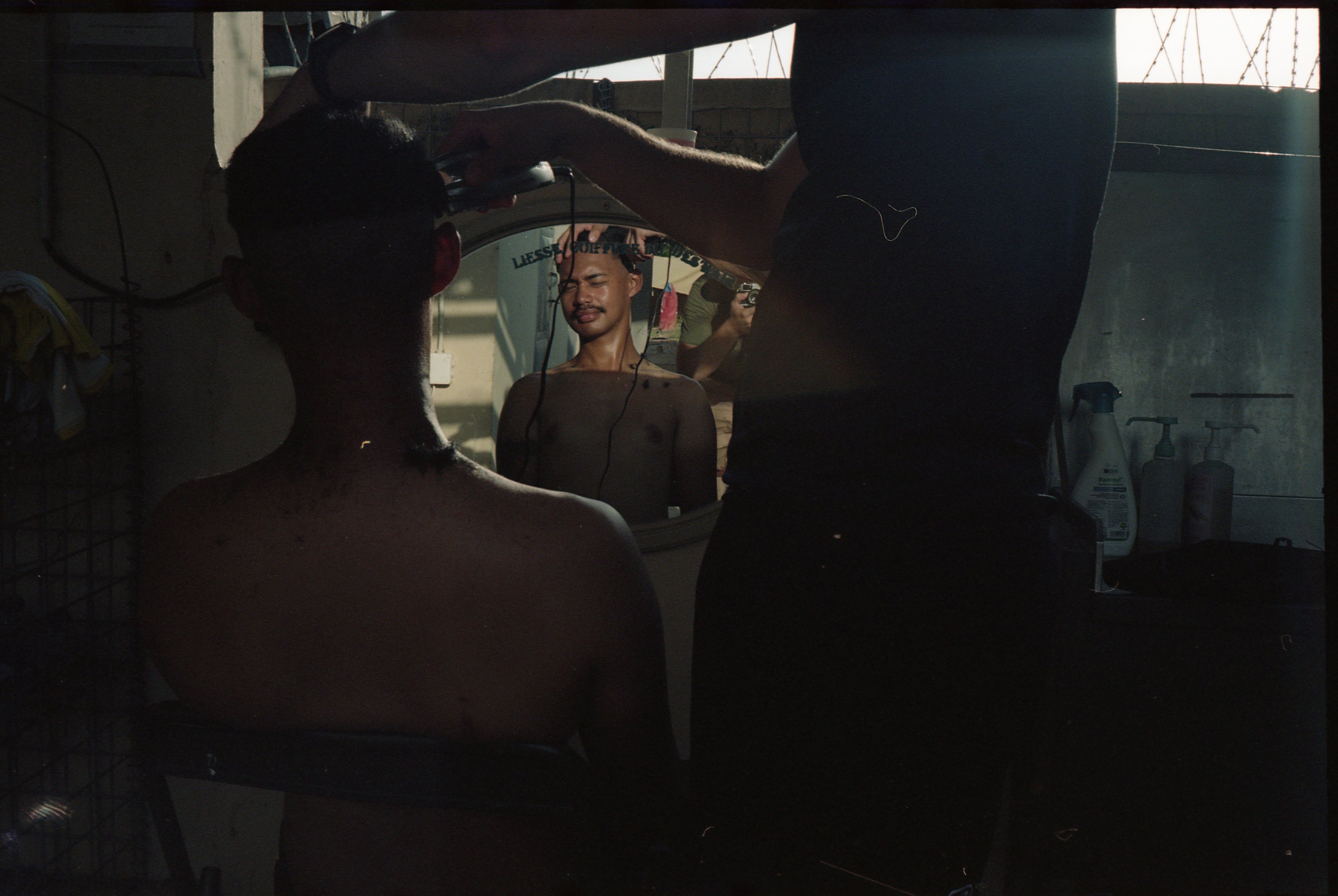 A soldier cutting a colleague's hair.