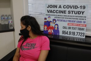 A person wearing a protective mask sits after participating in clinical trials for a COVID-19 vaccine in Florida in September.