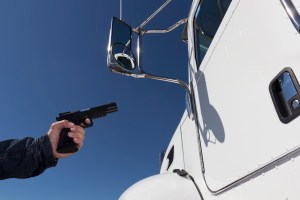 An image from the transportation industry of a truck driver being held up at gunpoint.