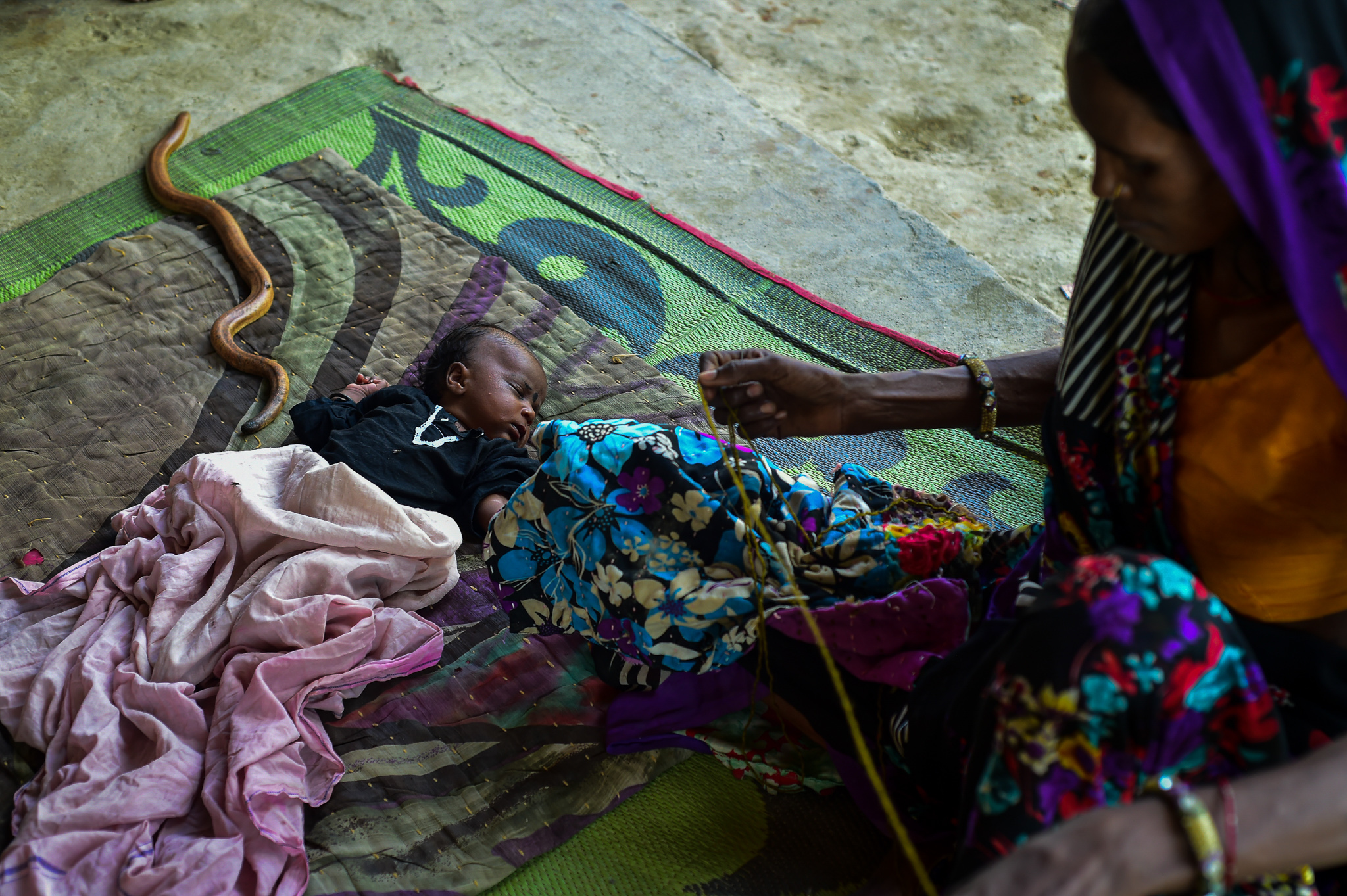 Bayi tidur di samping ular berkepala dua. Foto oleh Arun Sharma.