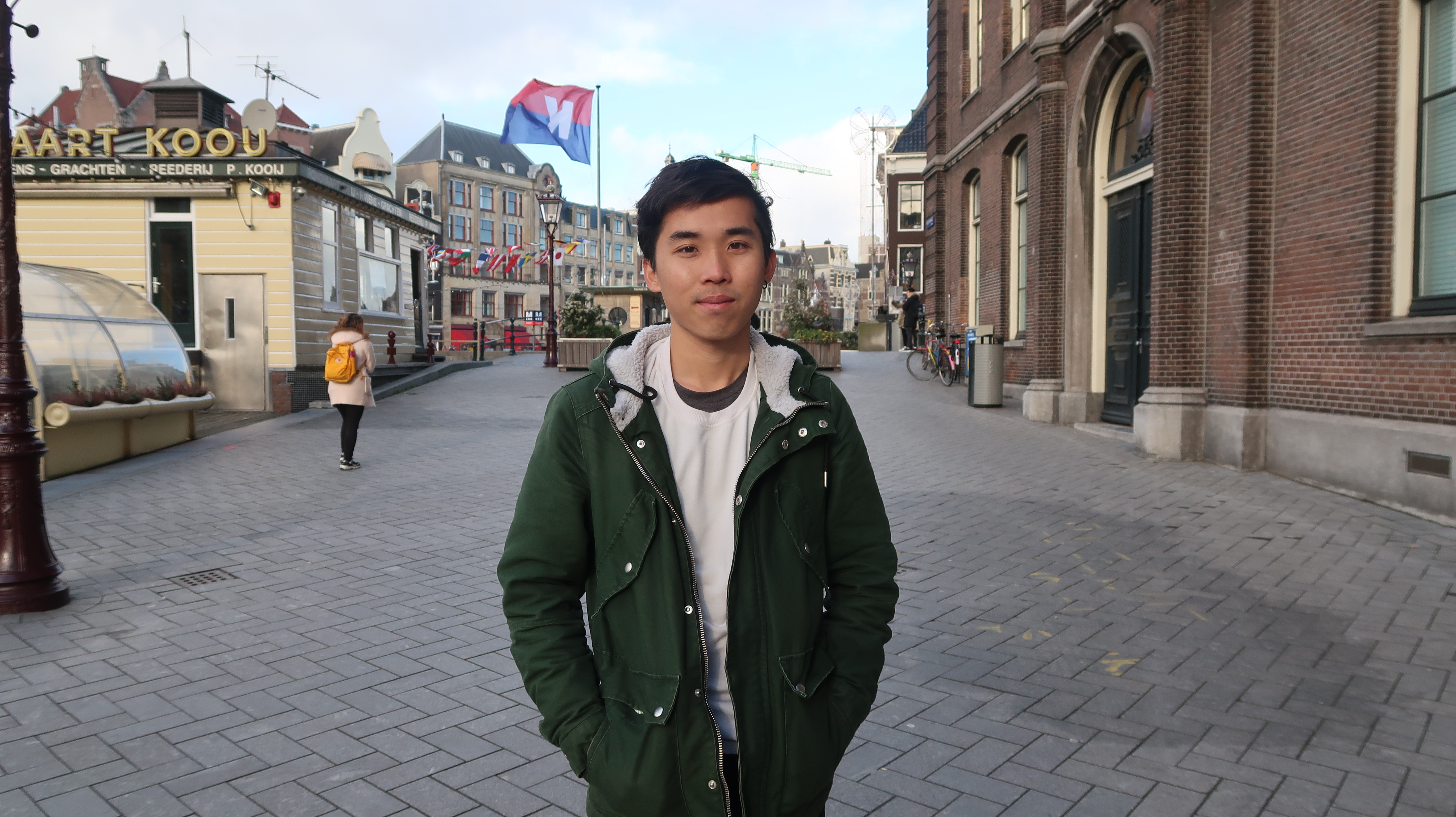 Ein junger Mann steht in einer ruhigen Straße Amsterdams