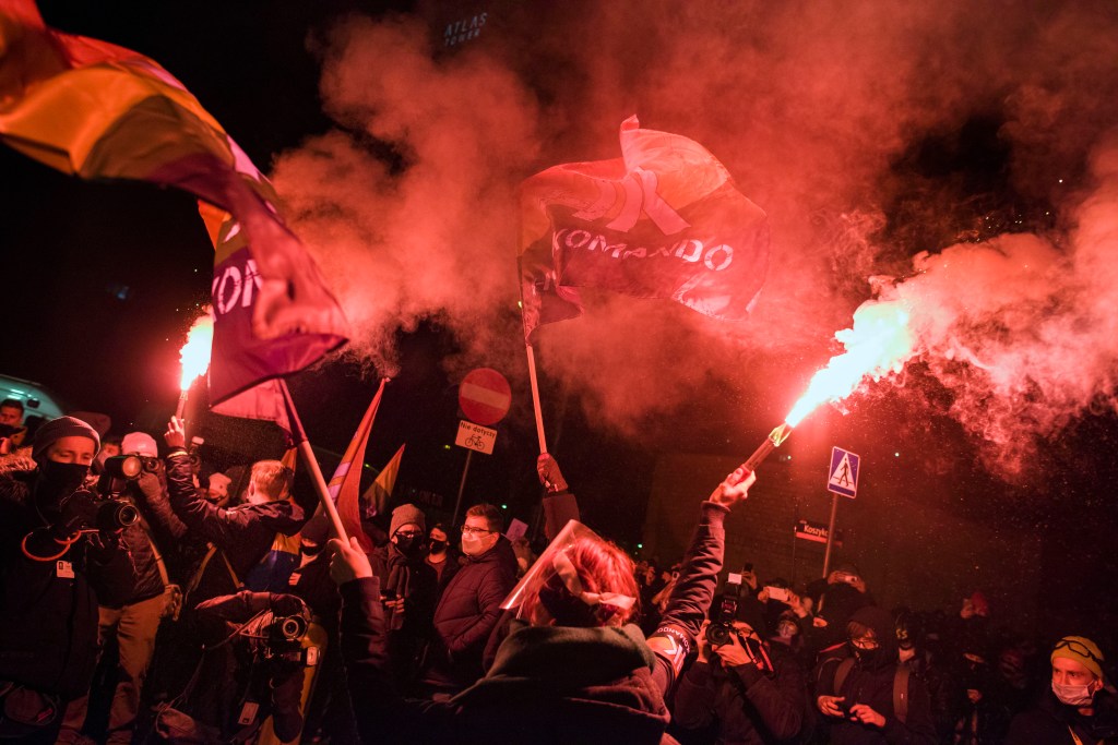 Protesters hold burning flares and flags during a demonstration against the abortion ban in Warsaw, organised by the Women's Strike.