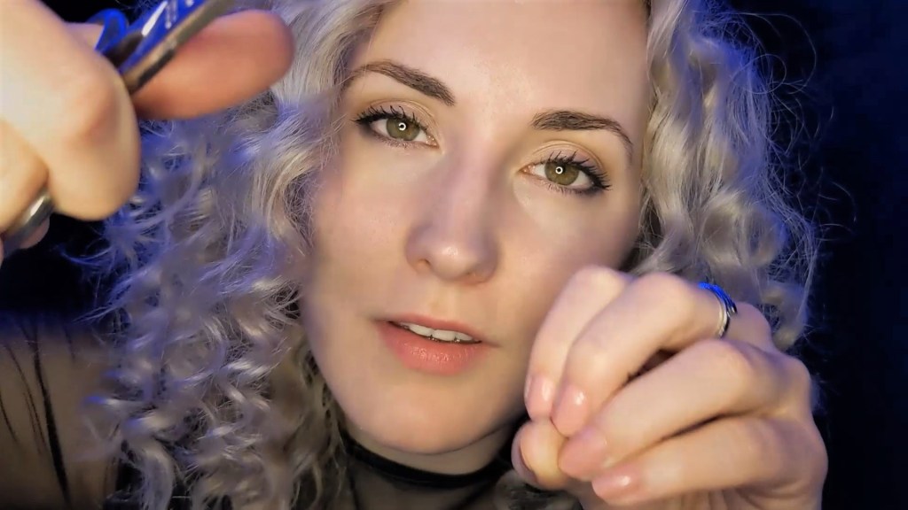 La creadora de videos ASMR Shortbread mira a la cámara sosteniendo un par de tijeras