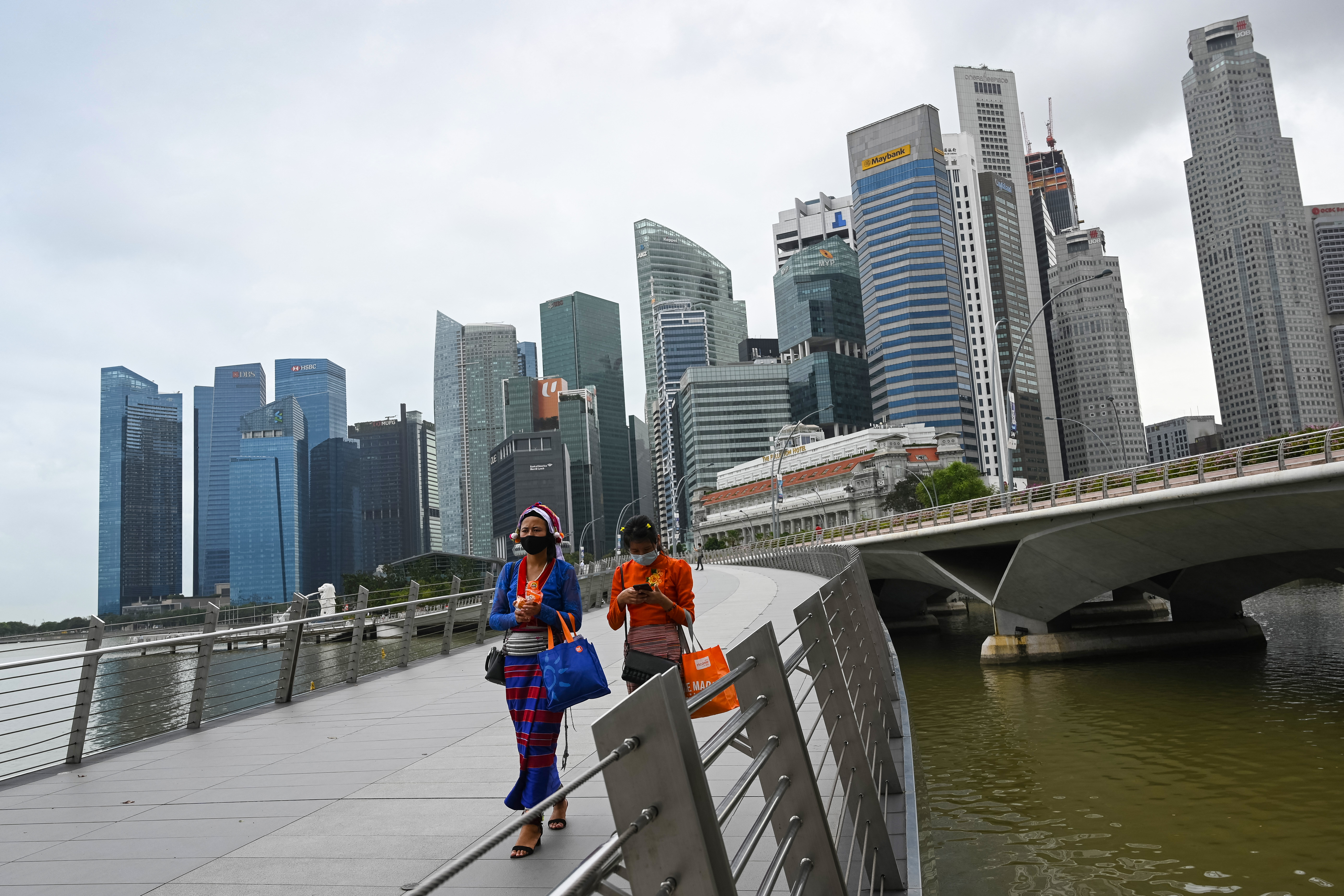 Women in traditional Burmese outfits walk across a bridge in Singapore. AFP: ROSLAN RAHMAN