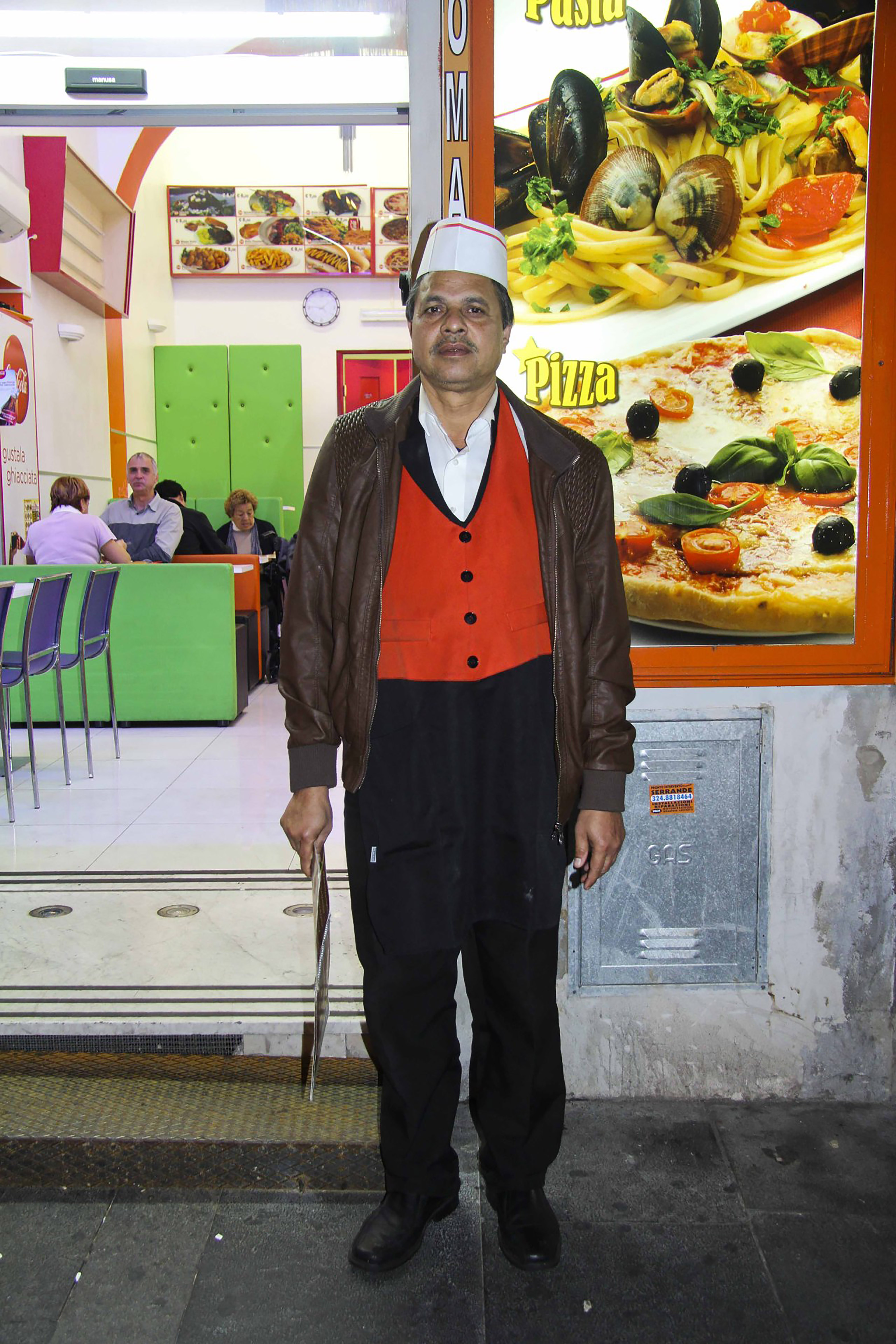 Ein Mitarbeiter eines Fastfood-Imbisses posiert in Arbeitskleidung im Hauptbahnhof Roms für ein Foto