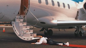CreaTyler laying on the ground next to the stairs of a private jet.