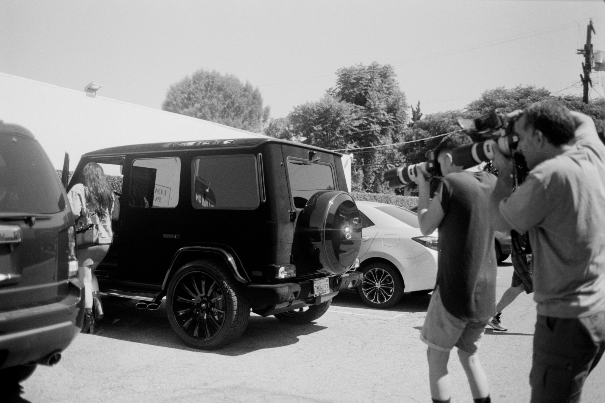 Kylie Jenner entering her car as paparazzi take photos of her.