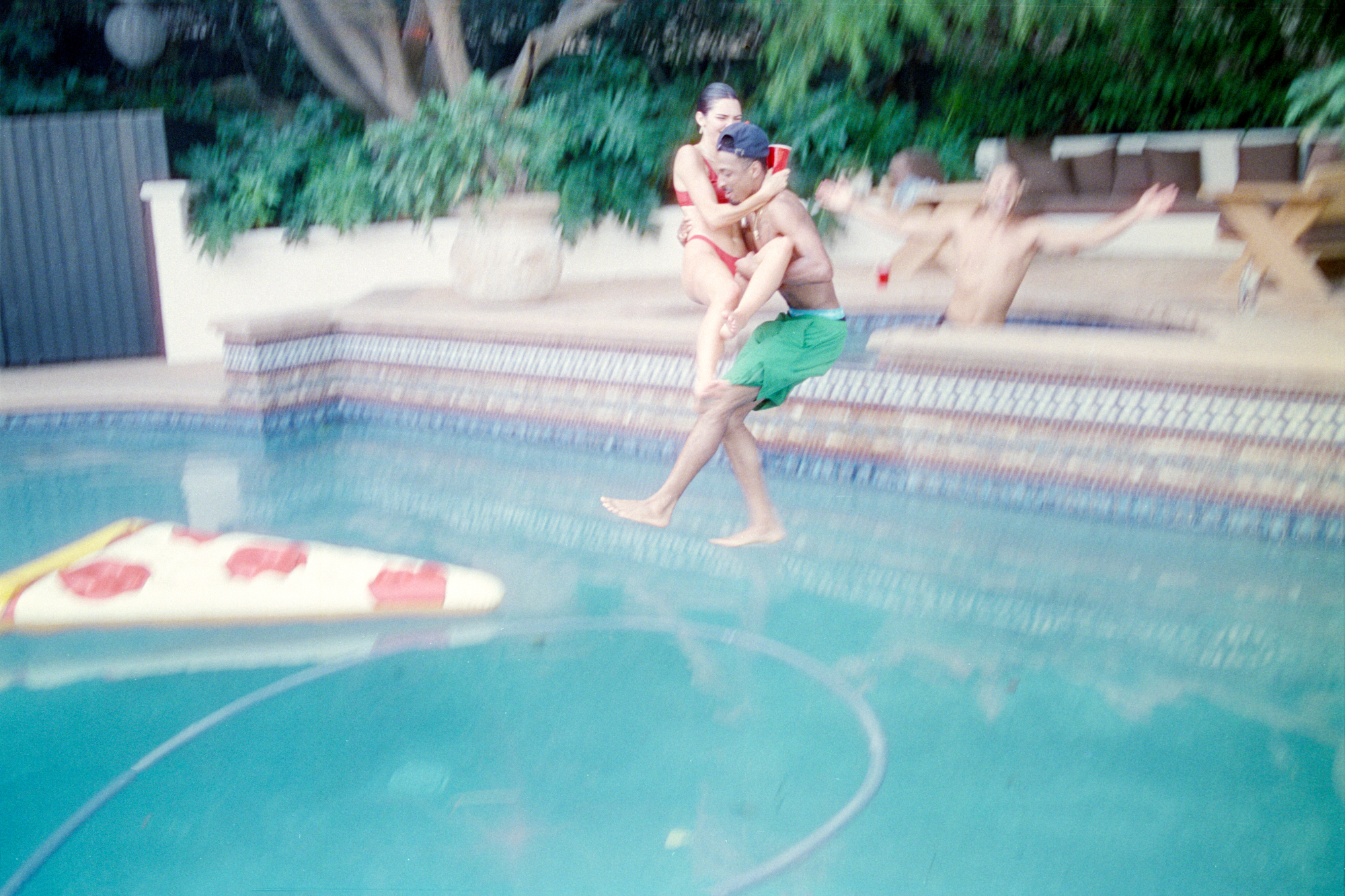 Kendall Jenner and Travis Bennett jumping into a pool.