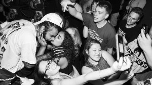 A fan kissing a performer as other fans take selfies. ​