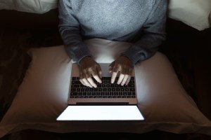 A laptop being used in bed, as seen from above.