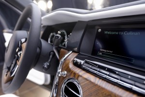The dashboard of a car with a display and brown wood panel trim, as seen from the passenger's side