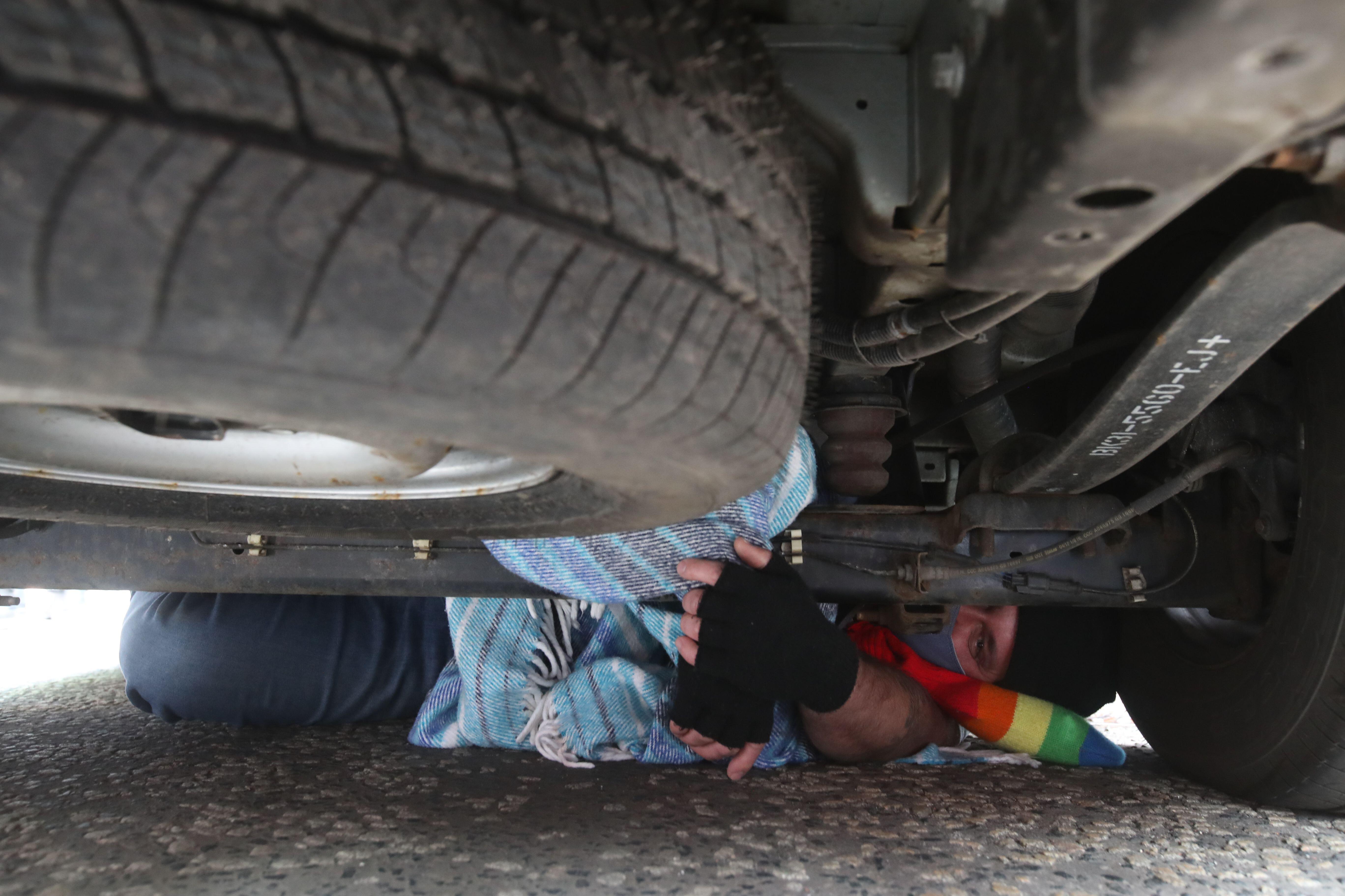 A person who placed themselves underneath the immigration van stopped by protesters in Kenmure Street, Glasgow. Photo: PA Images / Alamy Stock Photo