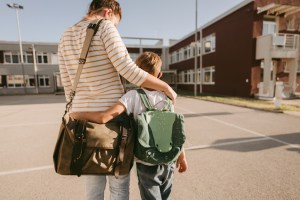 A schoolboy and his mother in the schoolyard; going back home after a long day at school.